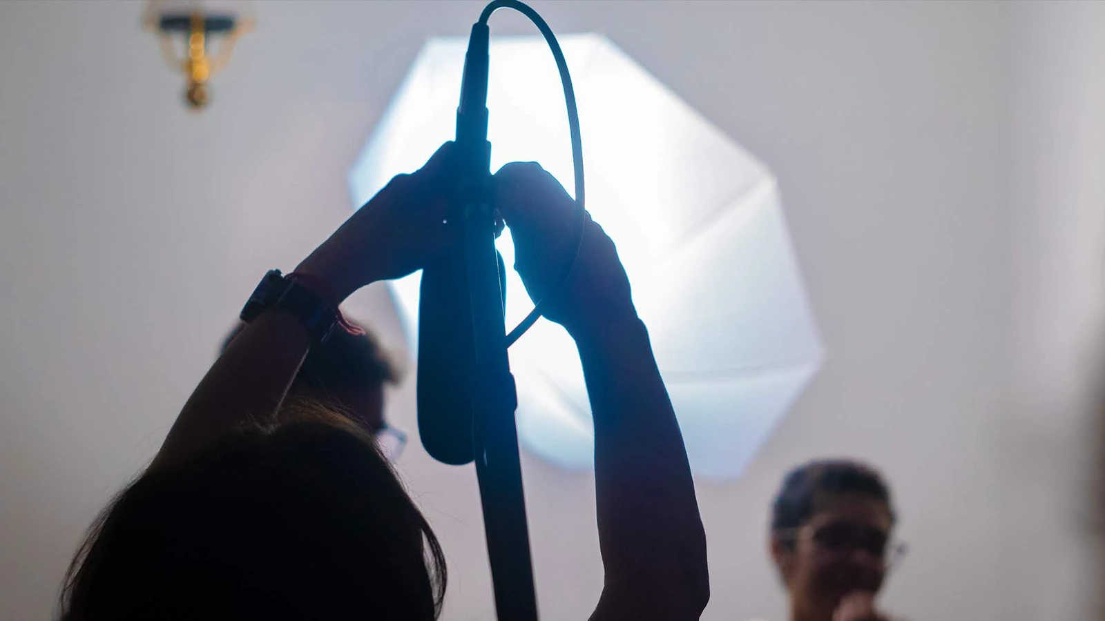 Microfone de boom preparado pela equipe diante de um softbox aceso.