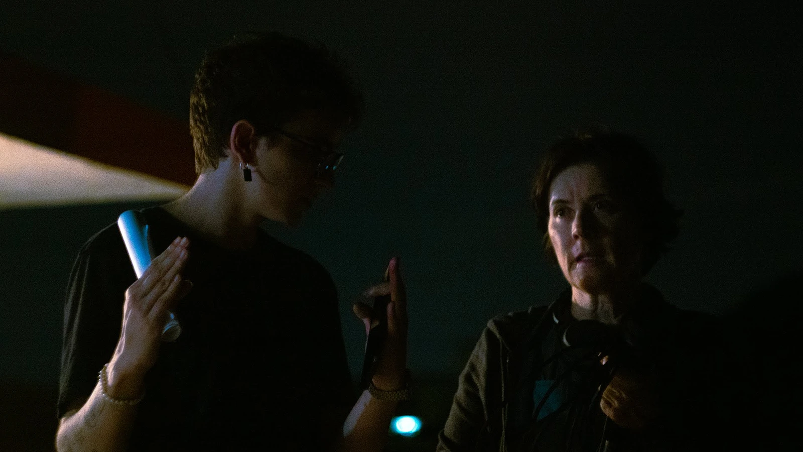 Conversa da equipe durante uma filmagem noturna, com luz azul ao fundo.
